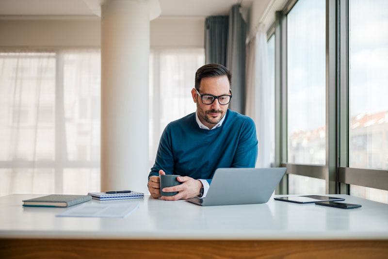 man at desk looking at his laptop